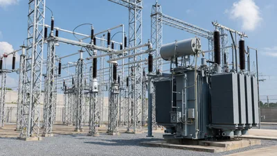 Outdoor air insulated substation switchyard featuring high-voltage gantry structures and circuit breakers