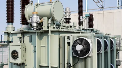 Detailed view of high-voltage transformer accessories including Buchholz relay, bushings, and cooling radiators.