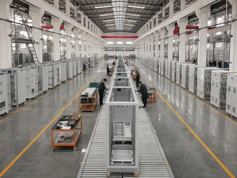 One-point perspective down the main MARS production hall with a conveyor line and workers